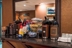 A hotel breakfast bar with coffee makers, condiment dispensers, and a variety of food items. - Red Roof Inn Augusta - Washington Road (Augusta)