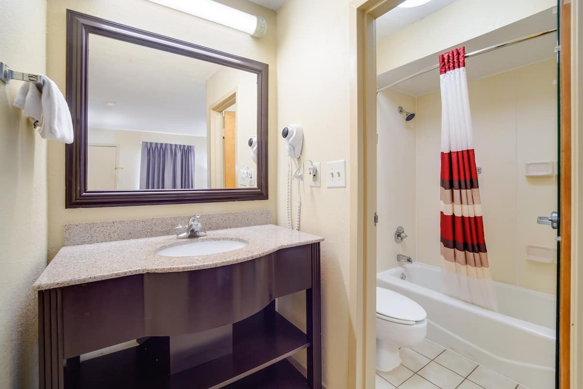 Un baño con lavamanos, espejo y ducha con cortina a rayas.