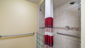 A shower with a red and white curtain, beige walls, and a tiled floor. - Red Roof Inn Augusta - Washington Road (Augusta)