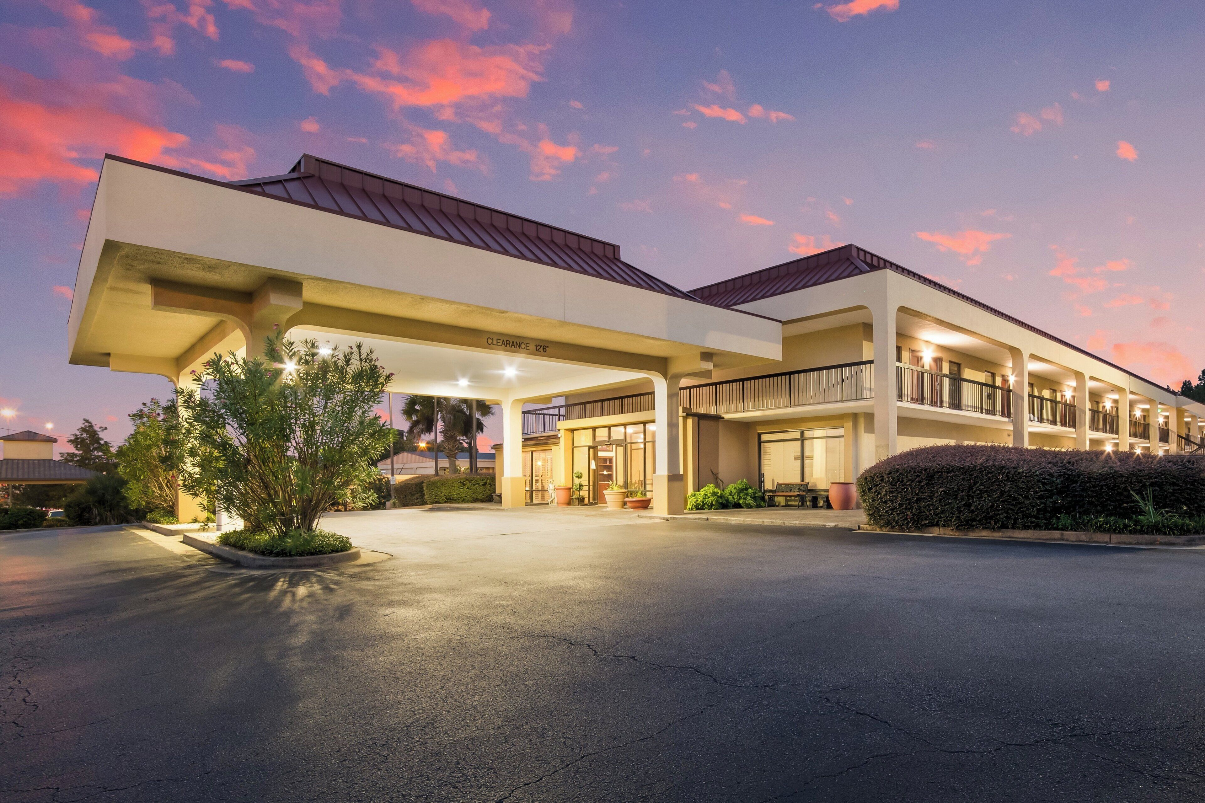 A hotel with a gas station, a covered parking area, and a well-lit entrance.