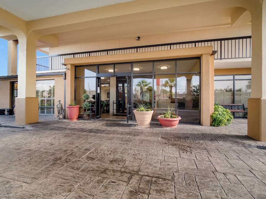 L’entrée d’un hôtel, avec une porte en verre, des plantes en pot et un sol carrelé.