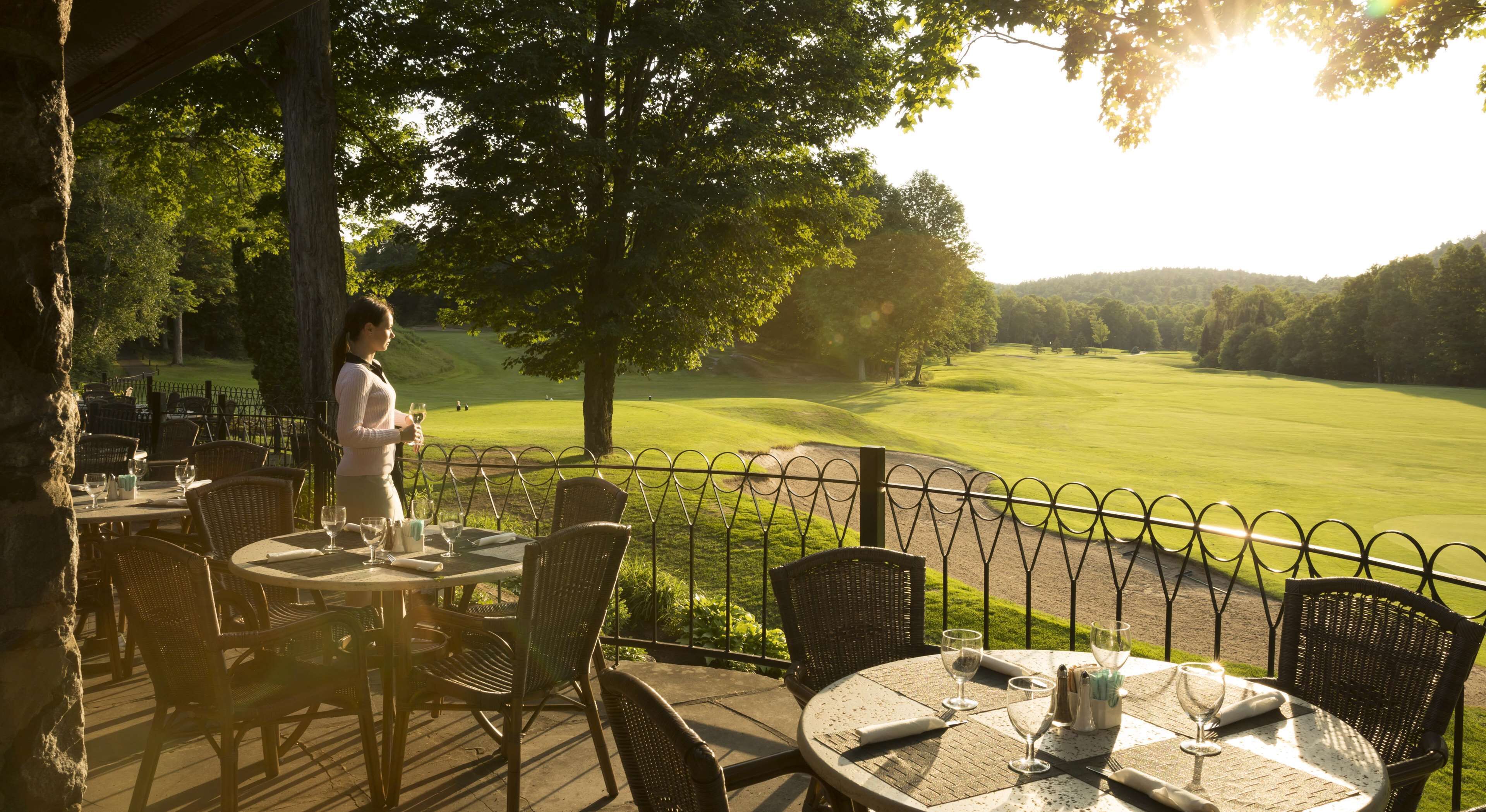 Ein Essbereich im Freien mit Tischen und Stühlen mit Blick auf einen Golfplatz.