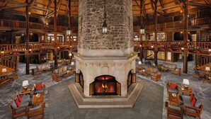 A spacious lobby with a stone fireplace, wooden furniture, and a high ceiling.