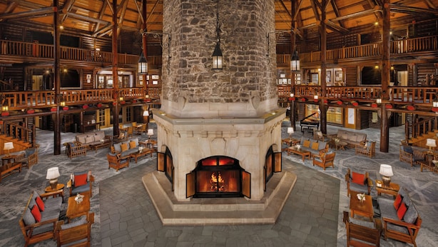 Un vestíbulo amplio con chimenea de piedra, muebles de madera y un techo alto.