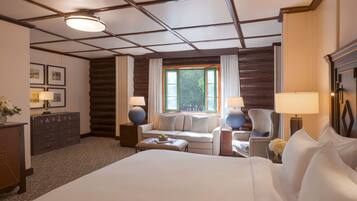 A hotel room with a large bed, a sofa, a chair, a desk, and a window with curtains.