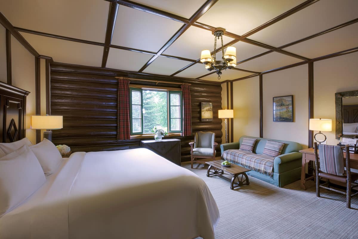 Een hotelkamer met een groot bed, een bank, een stoel, een bureau en een kroonluchter.