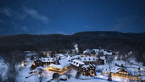 Un albergue cubierto de nieve con varias construcciones, una torre central y una entrada bien iluminada.
