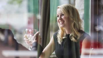 Una persona sentada a una mesa con un plato de comida y una copa de vino.