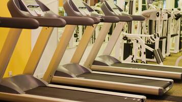 A row of treadmills in a gym with mirrors on the walls.
