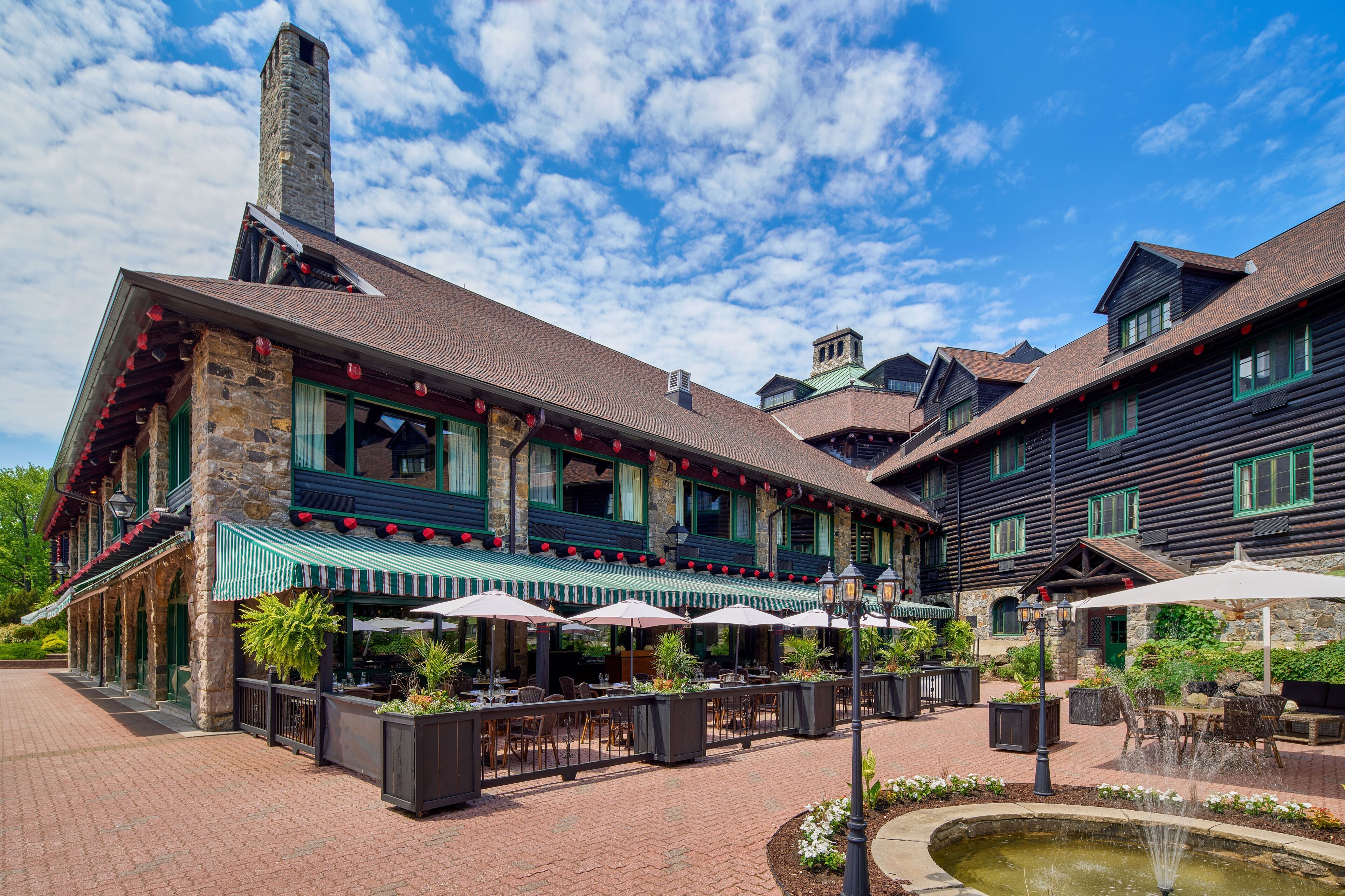 A brick building with outdoor seating, a stone chimney, and a fountain.