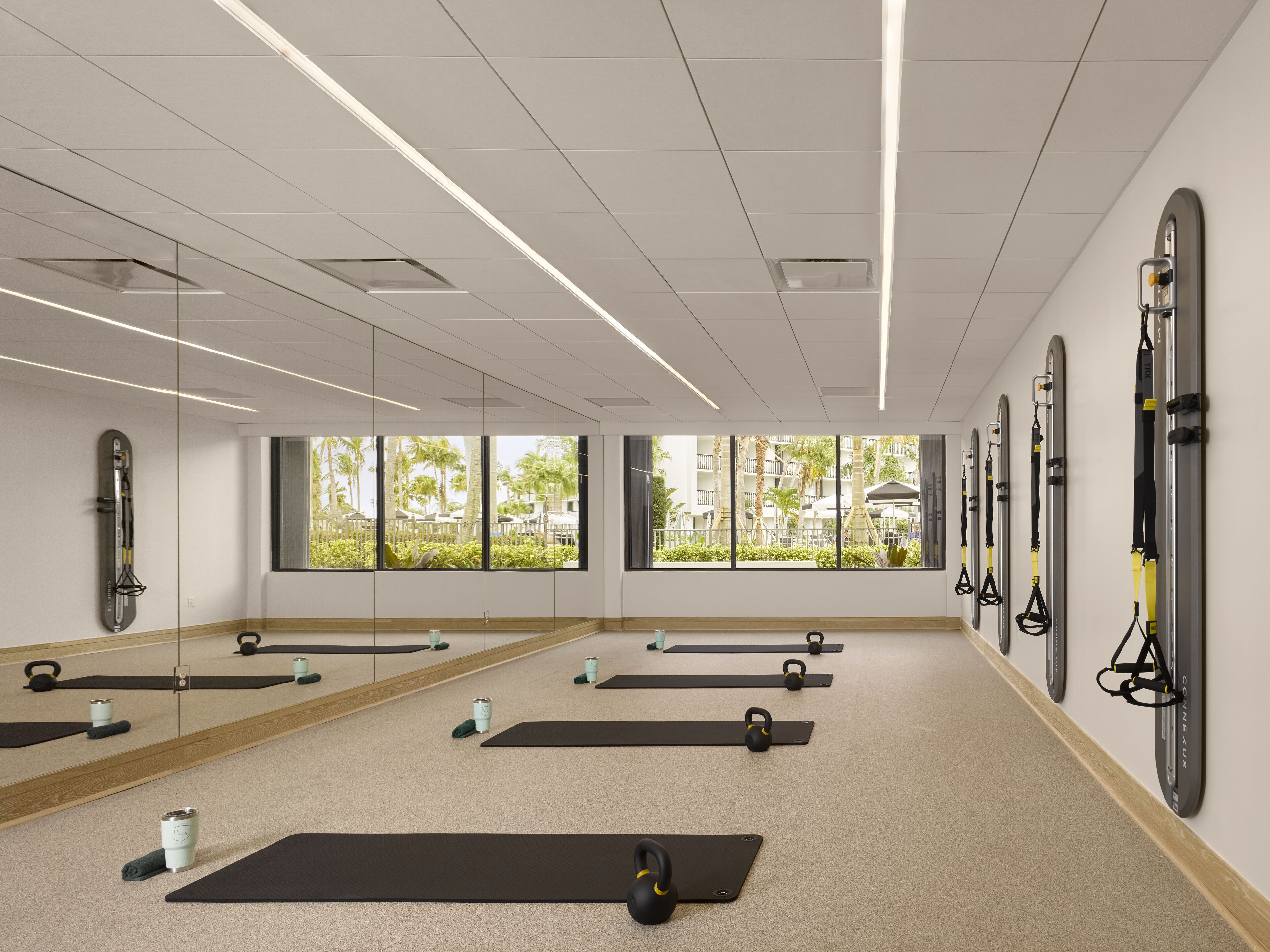 A spacious gym with multiple exercise mats, kettlebells, and a large mirror.