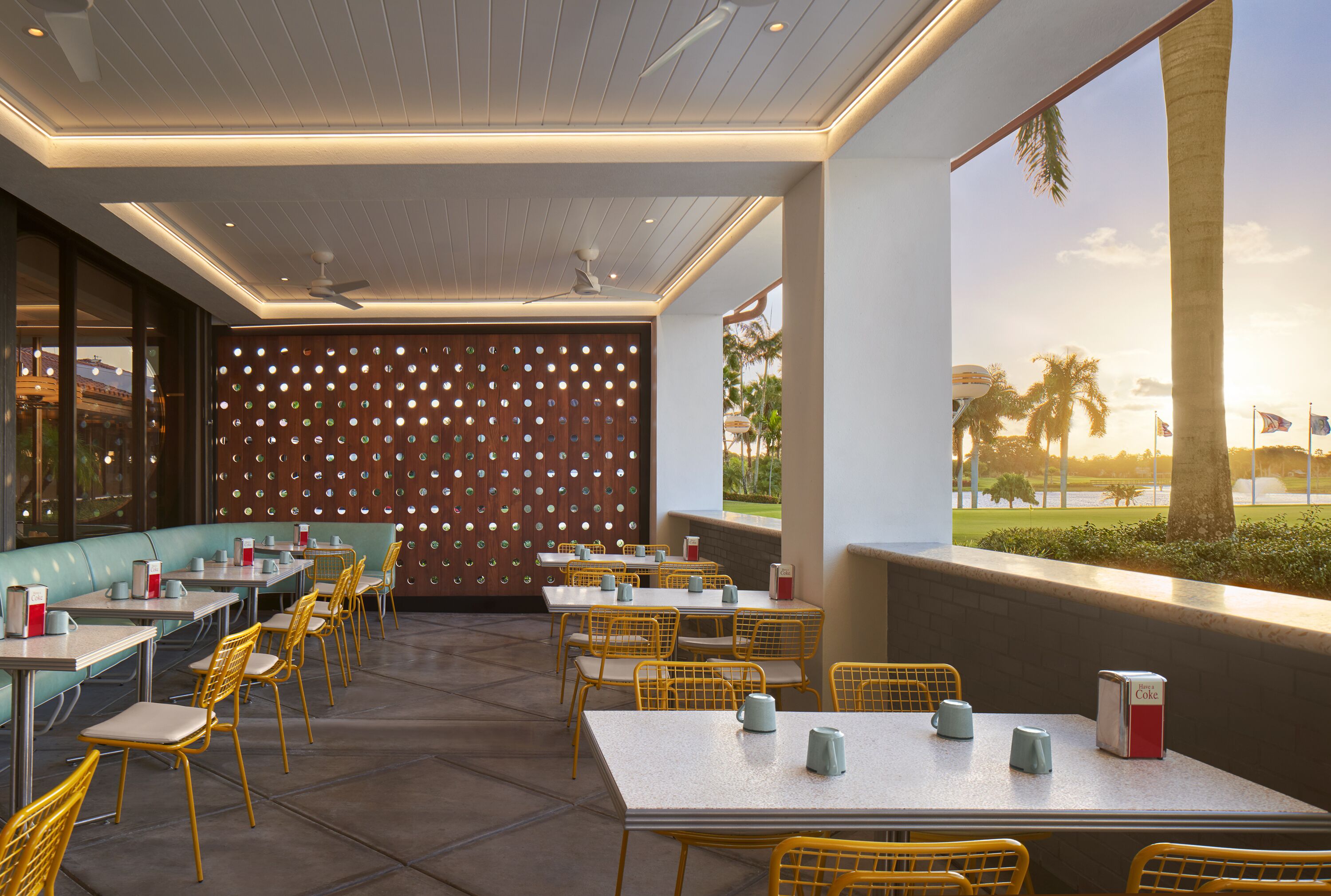 Un restaurante con terraza, mesas y sillas, y una pared decorativa.
