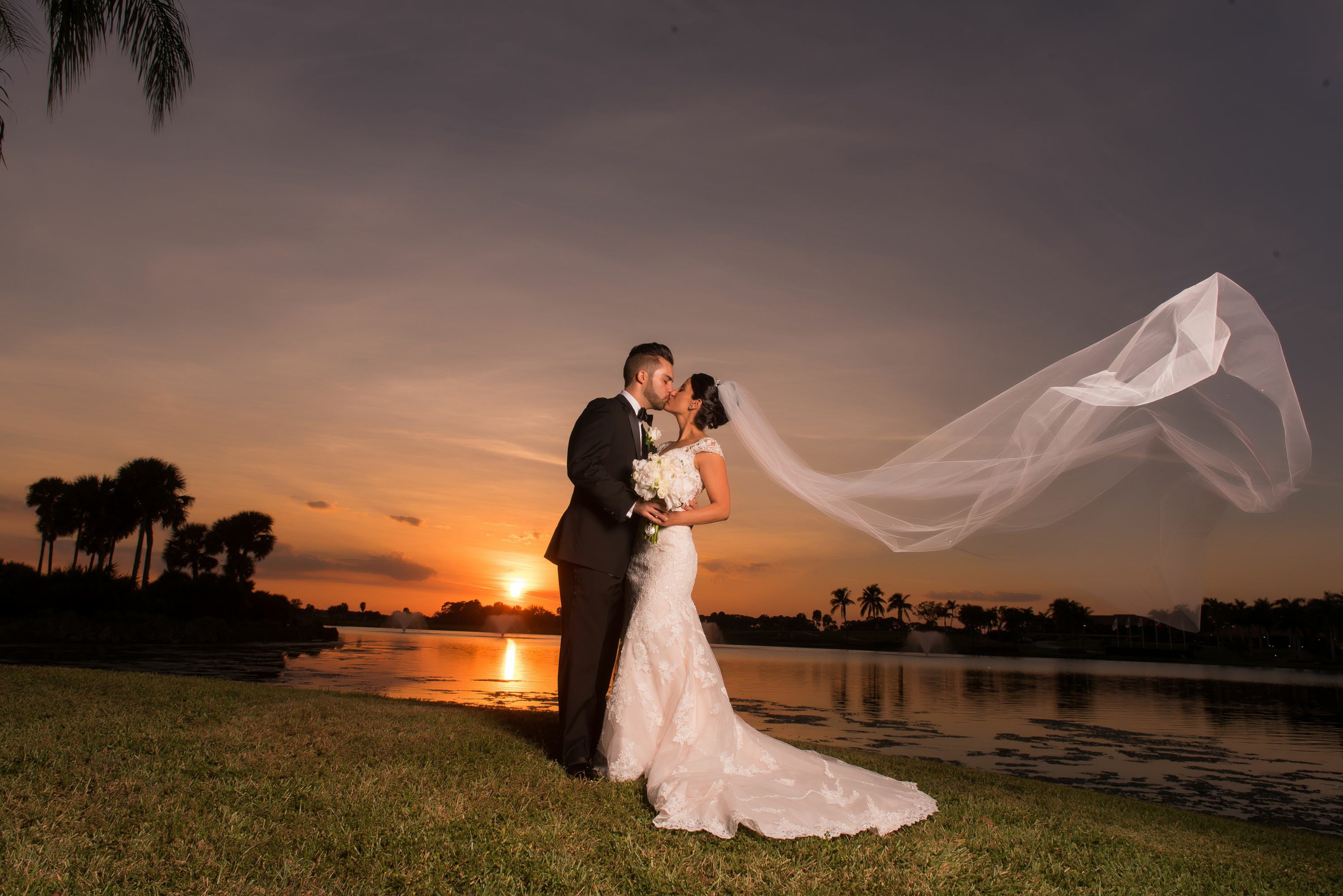 A couple embracing by a lake at sunset.