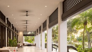 A covered outdoor area with seating, ceiling fans, and large windows overlooking greenery. - PGA National Resort  (Palm Beach Gardens)
