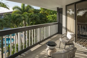 Enjoy a serene view of the pool surrounded by lush greenery from this balcony.