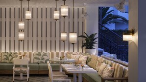 A modern lounge area with a green sofa, white chairs, and a table with drinks and flowers. - PGA National Resort  (Palm Beach Gardens)