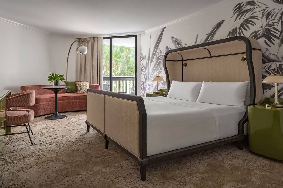 Een hotelkamer met een bed, een bank, een stoel, een tafel en een lamp.