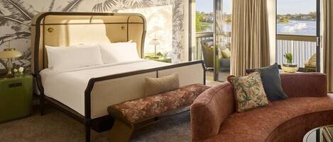 A hotel room with a bed, a bench, a sofa, and a view of the outdoors.