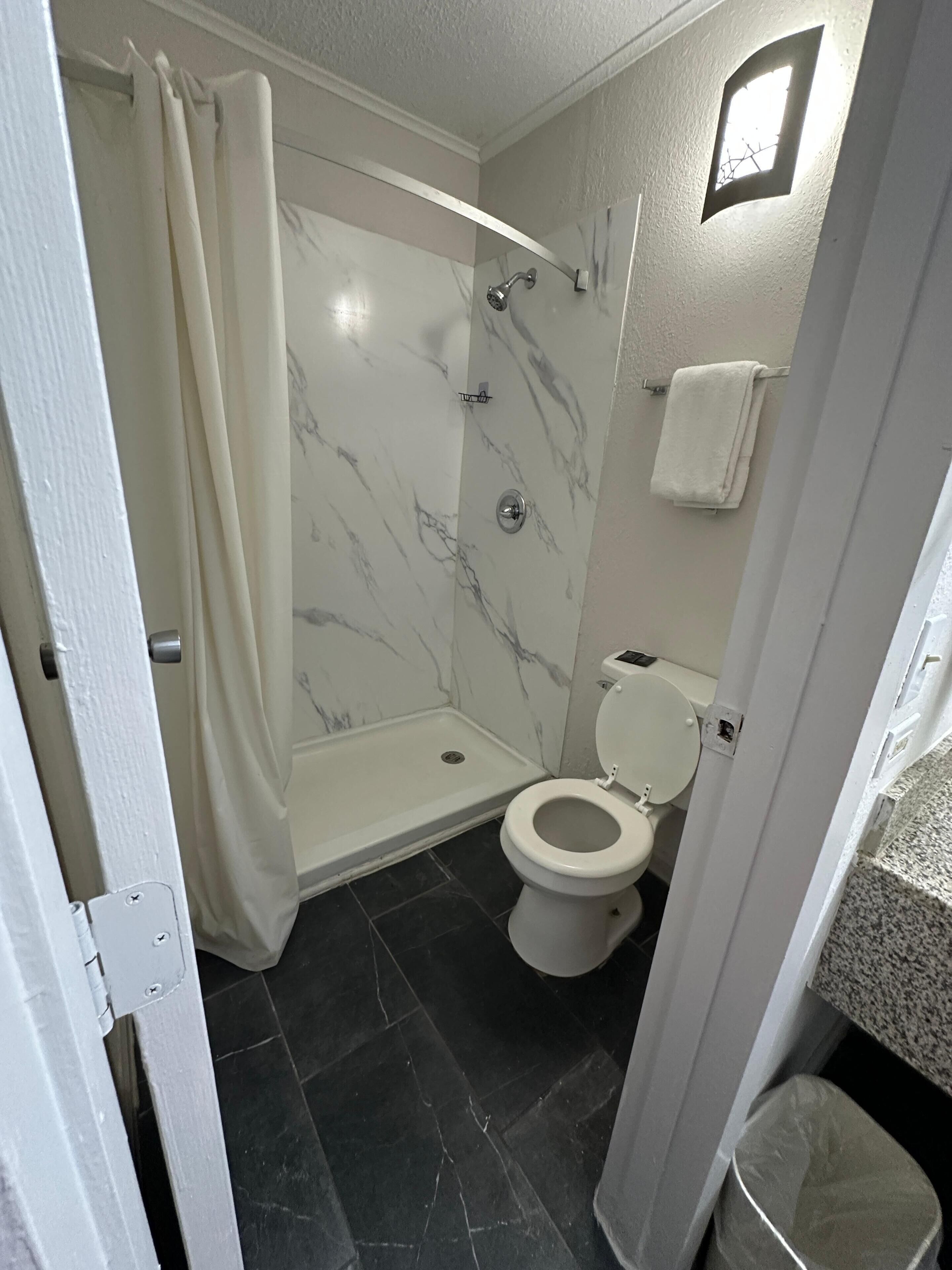 A bathroom with a shower, toilet, and marble walls.