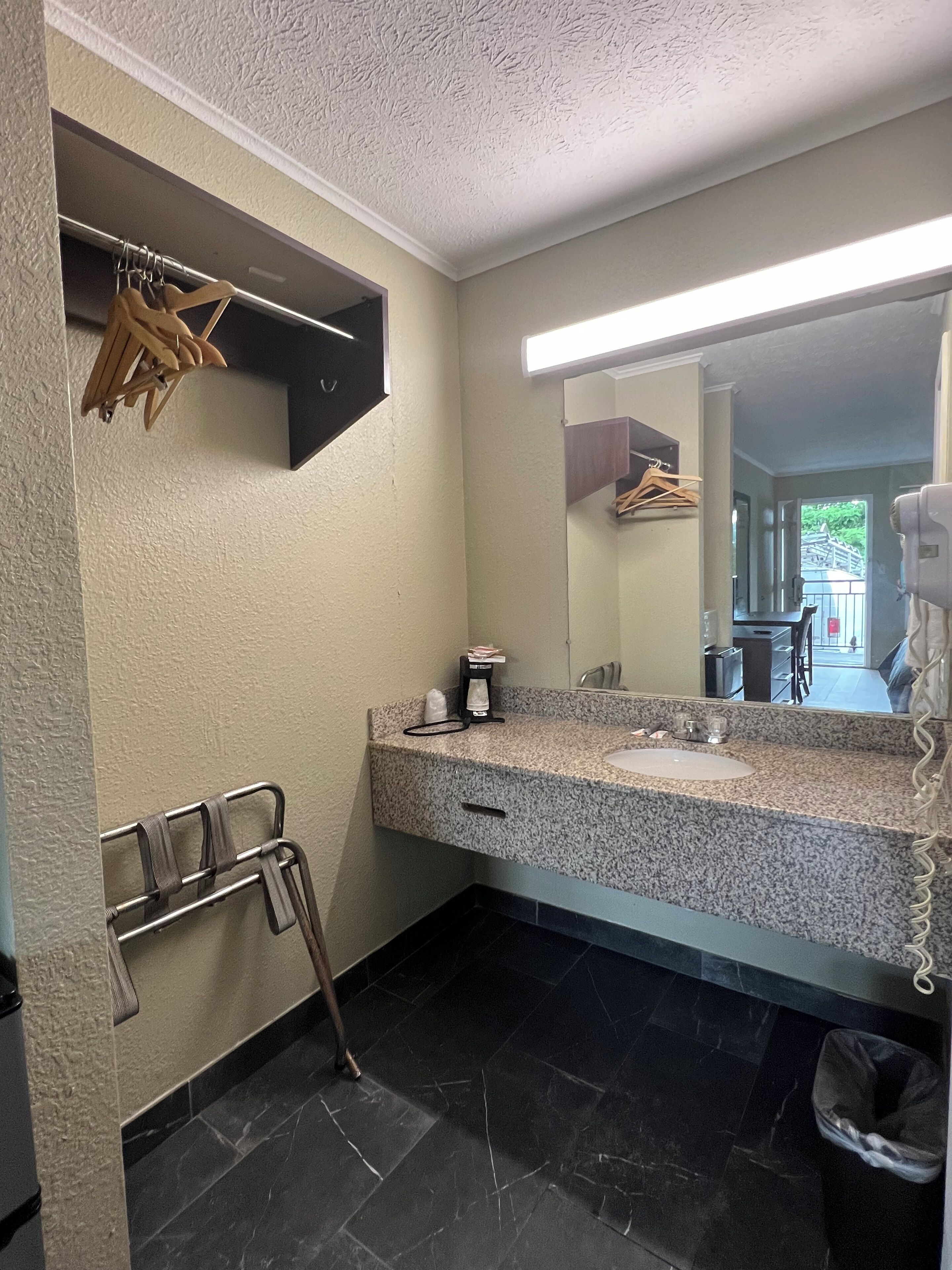 Une salle de bain dotée d’un comptoir en granit, d’un lavabo, d’un miroir, d’un porte-serviettes et d’un espace douche.