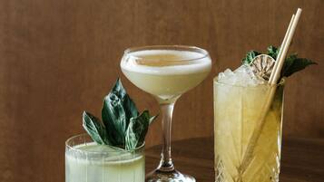 Trois cocktails sur une table en bois, avec un fond marron.