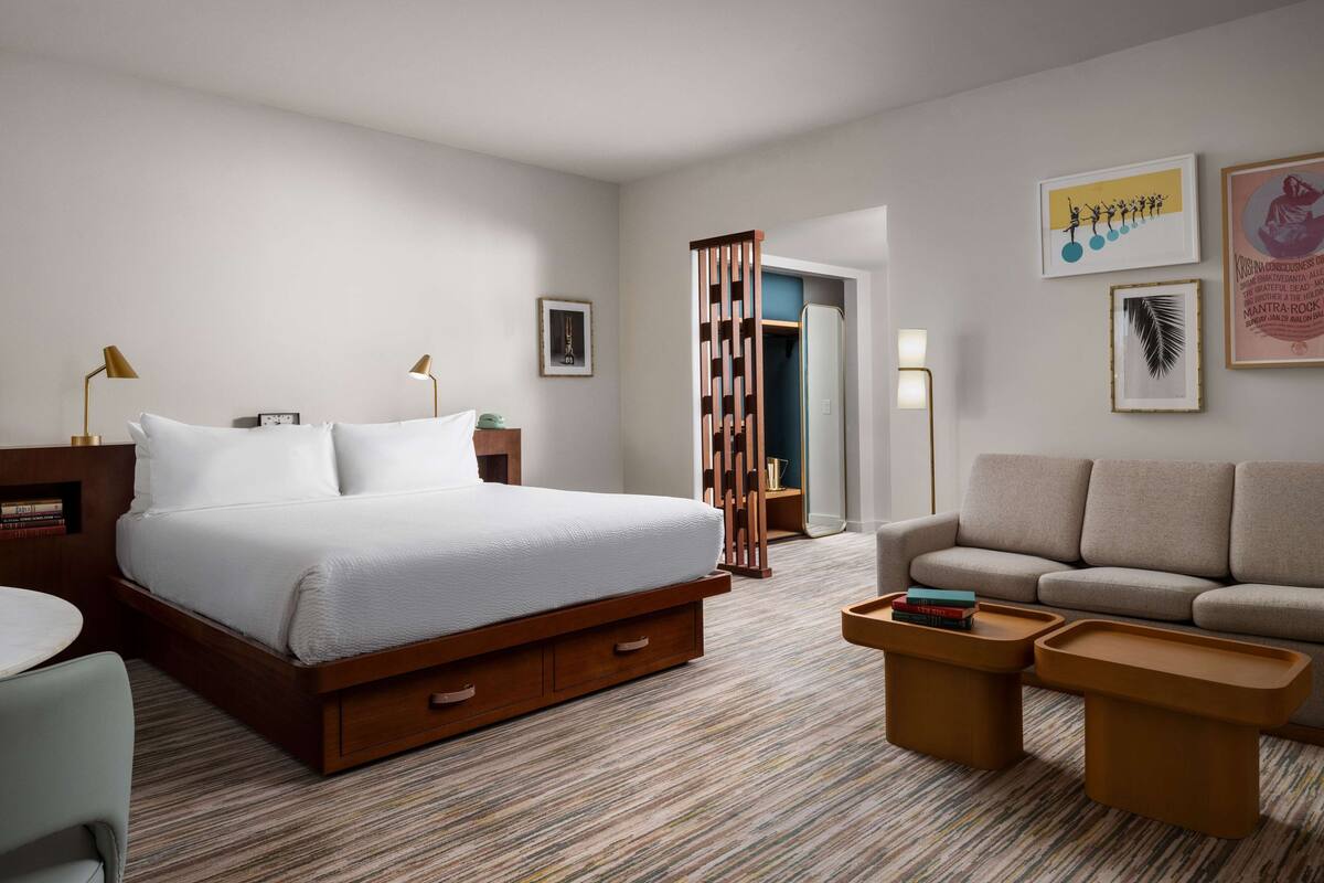 Una habitación de hotel con una cama grande, un sofá, una mesa de centro y un escritorio con lámpara.