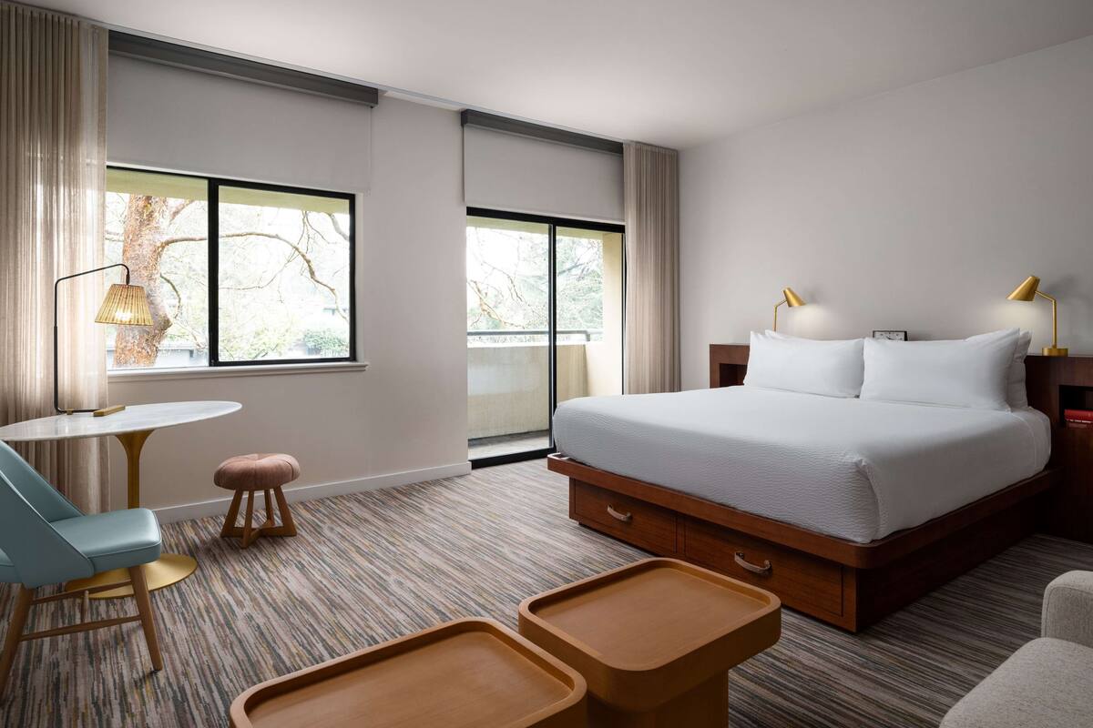 Una habitación de hotel con una cama grande, un escritorio, una silla y una mesita.