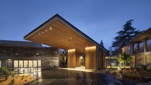 A modern building with a large overhang, stone facade, and a well-lit entrance.