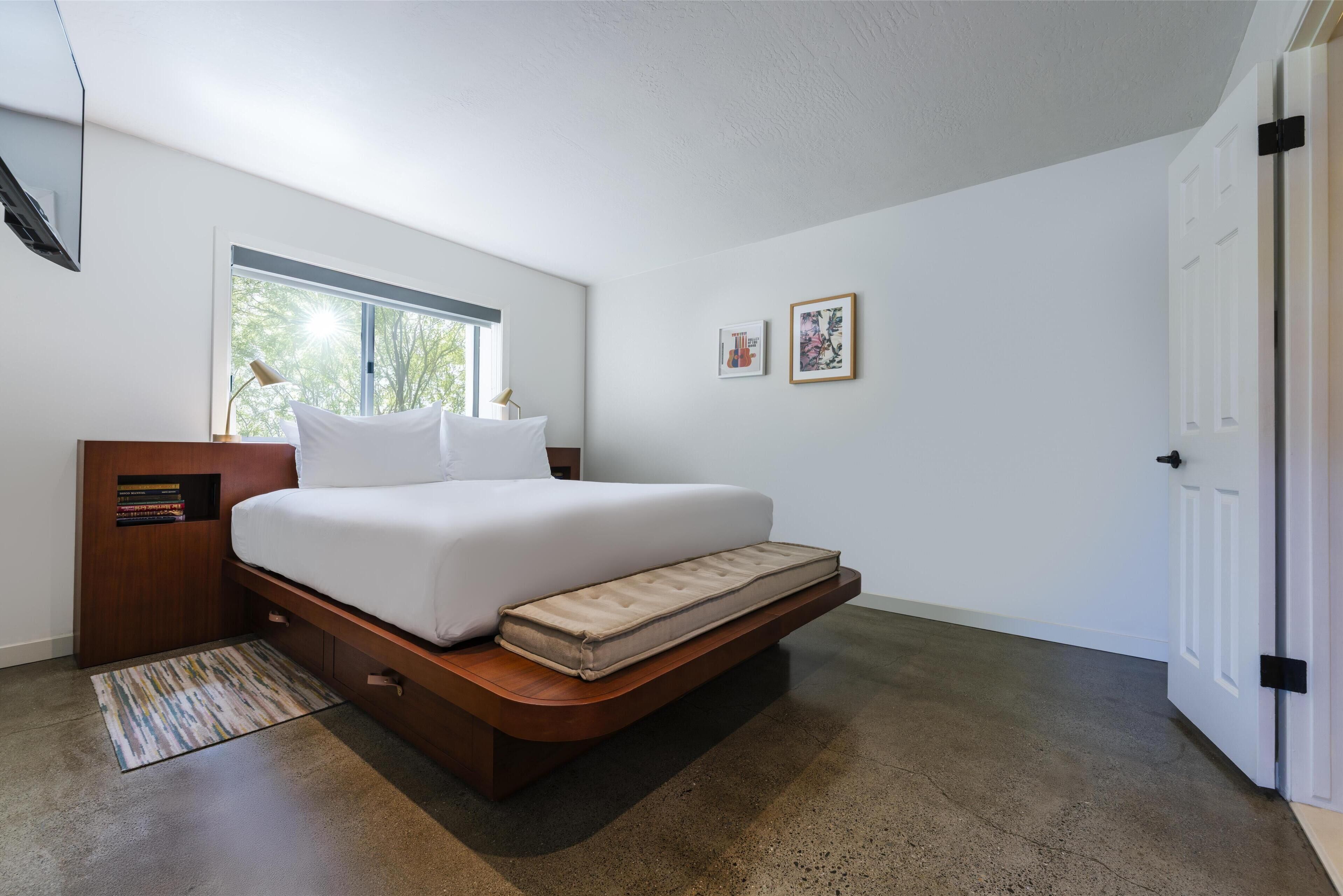 Un dormitorio moderno con cama, mesita de noche, ventana y puerta.