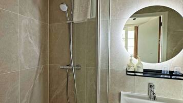 A bathroom with a glass-enclosed shower, a sink, and a mirror.