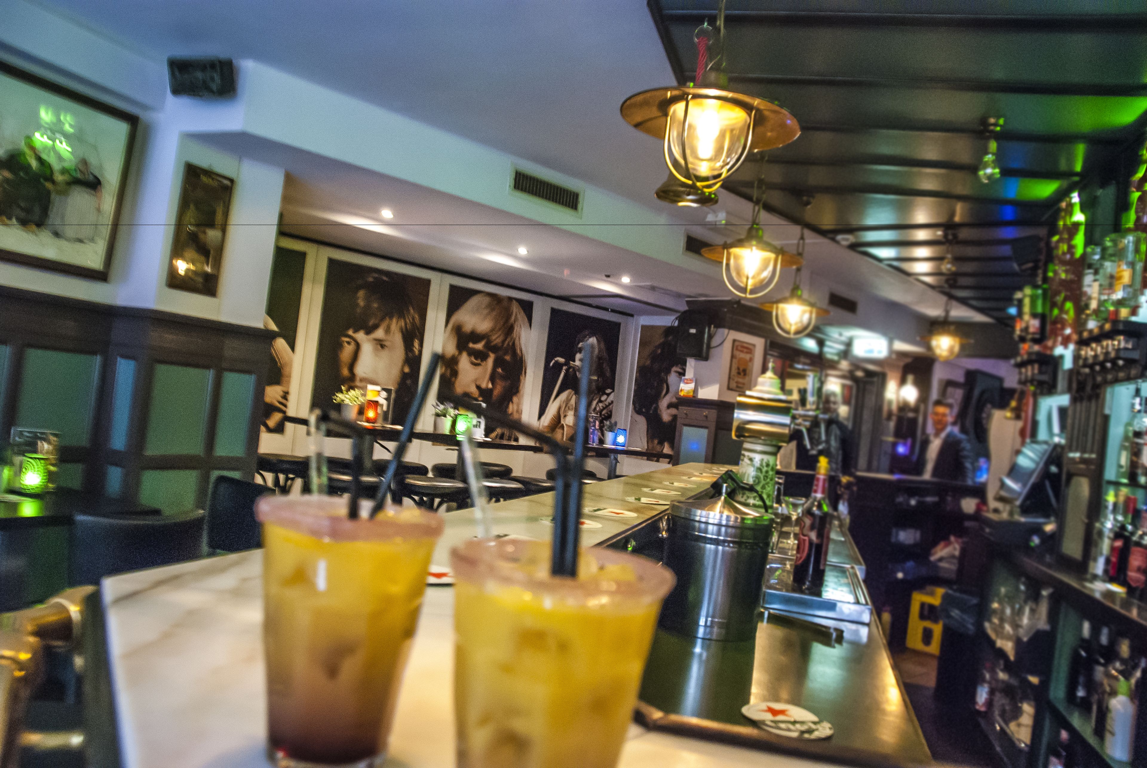 Una zona de bar con bebidas en una bandeja, un bartender y estantes llenos de botellas.