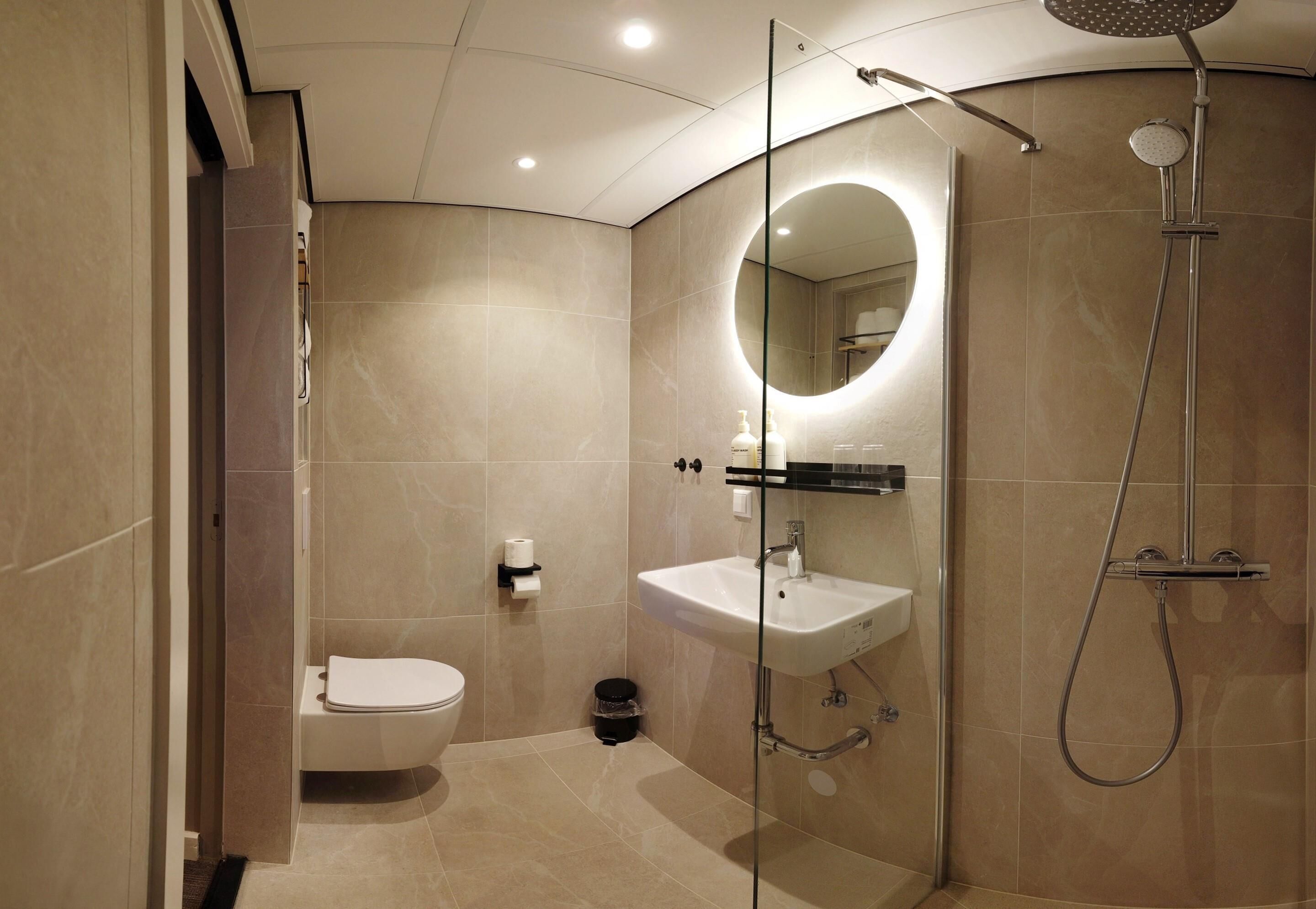 A modern bathroom with a glass-enclosed shower, a white sink, and a toilet.