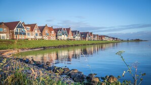 A row of traditional houses by a calm lake with a grassy shoreline. - Hotel Spaander, BW Signature Collection (Volendam)