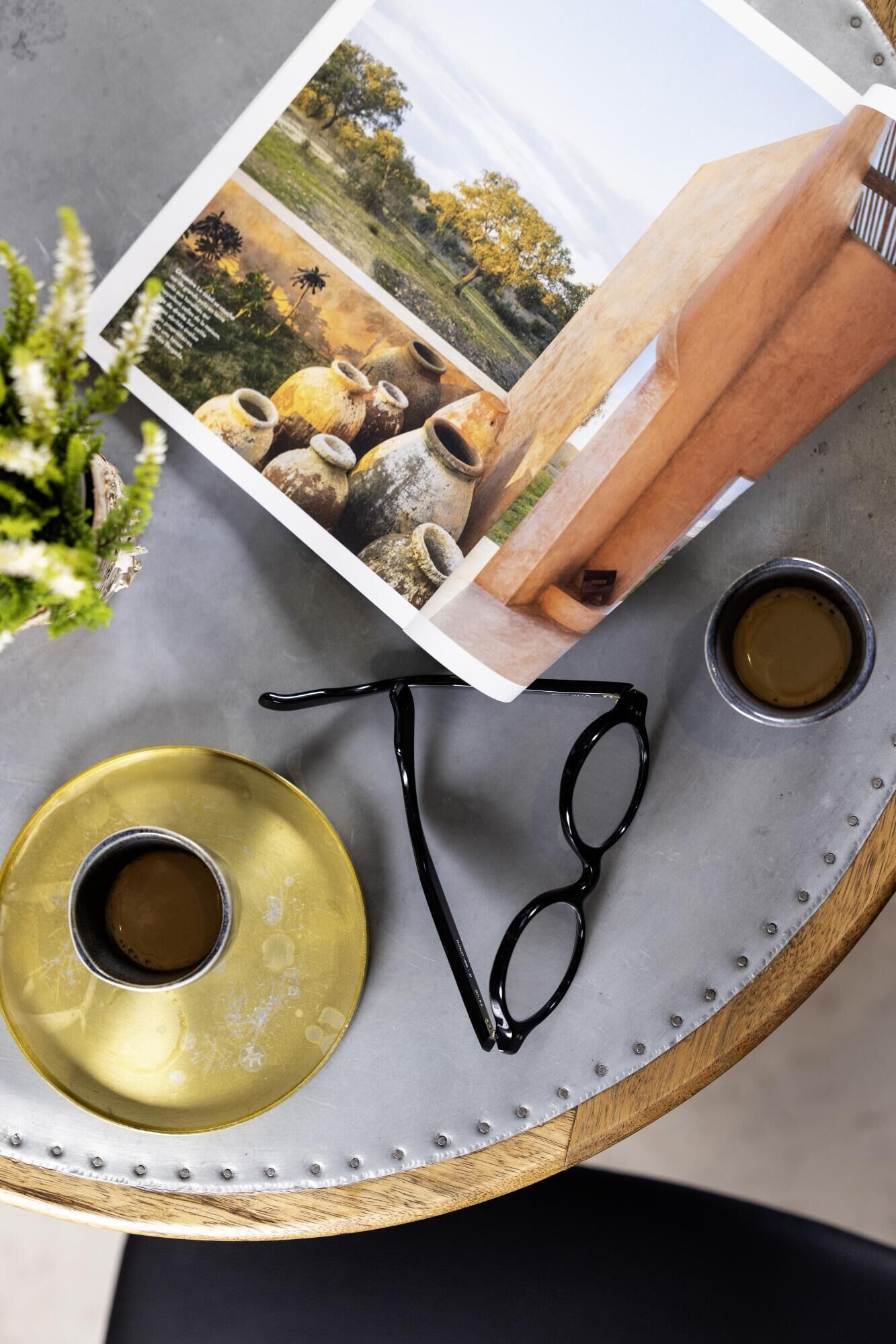 Una bandeja con un par de lentes, dos tazas pequeñas y una fotografía.