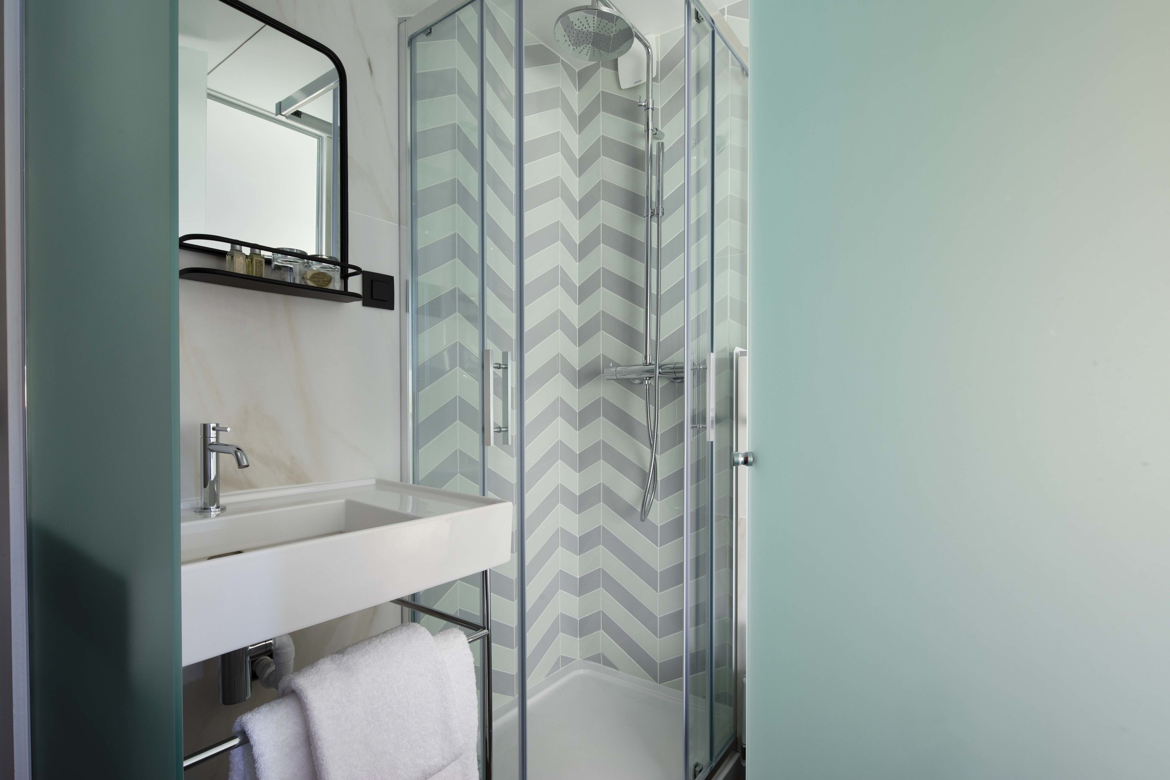 Une salle de bain moderne avec une douche à parois de verre, un lavabo blanc et un miroir.
