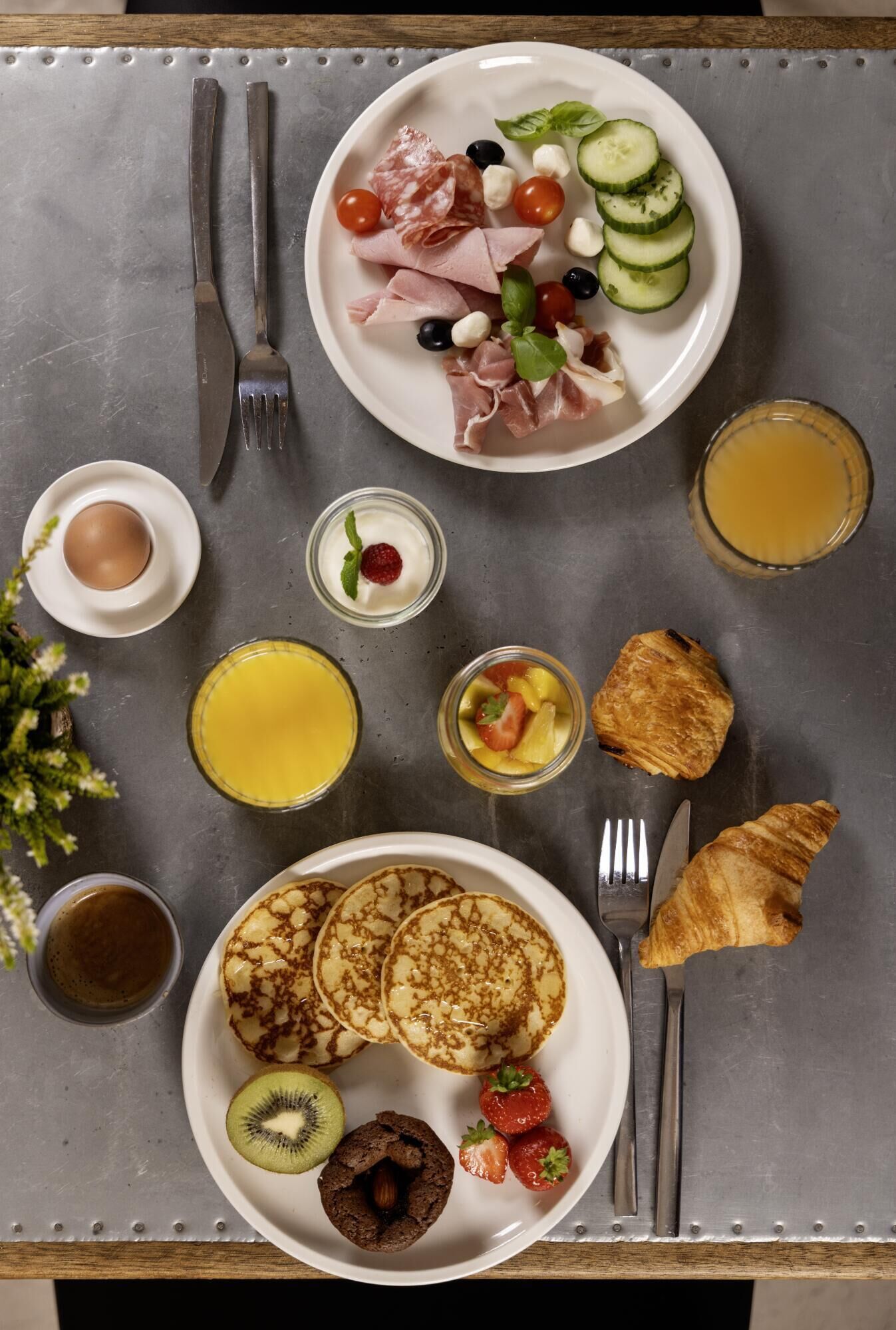 A breakfast setting with plates of food, drinks, and utensils on a table.