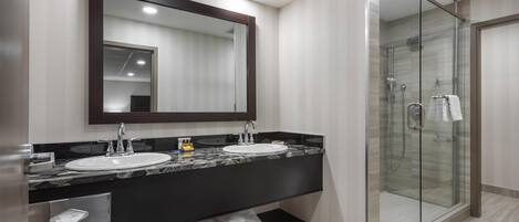 A modern bathroom with a double sink, a large mirror, and a glass-enclosed shower.