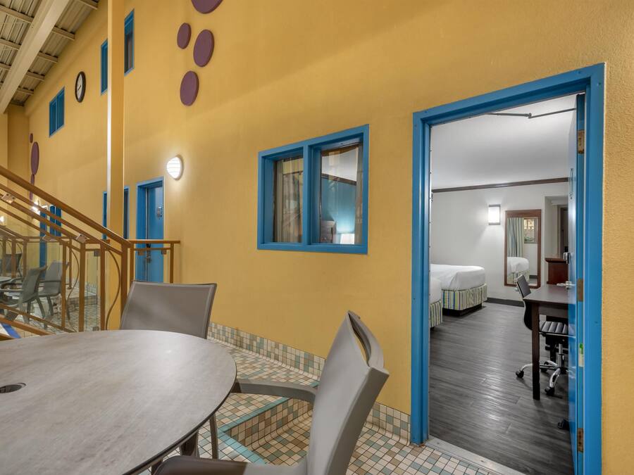 A hotel room with a bed, a desk, and a chair. There is a staircase leading to another level.