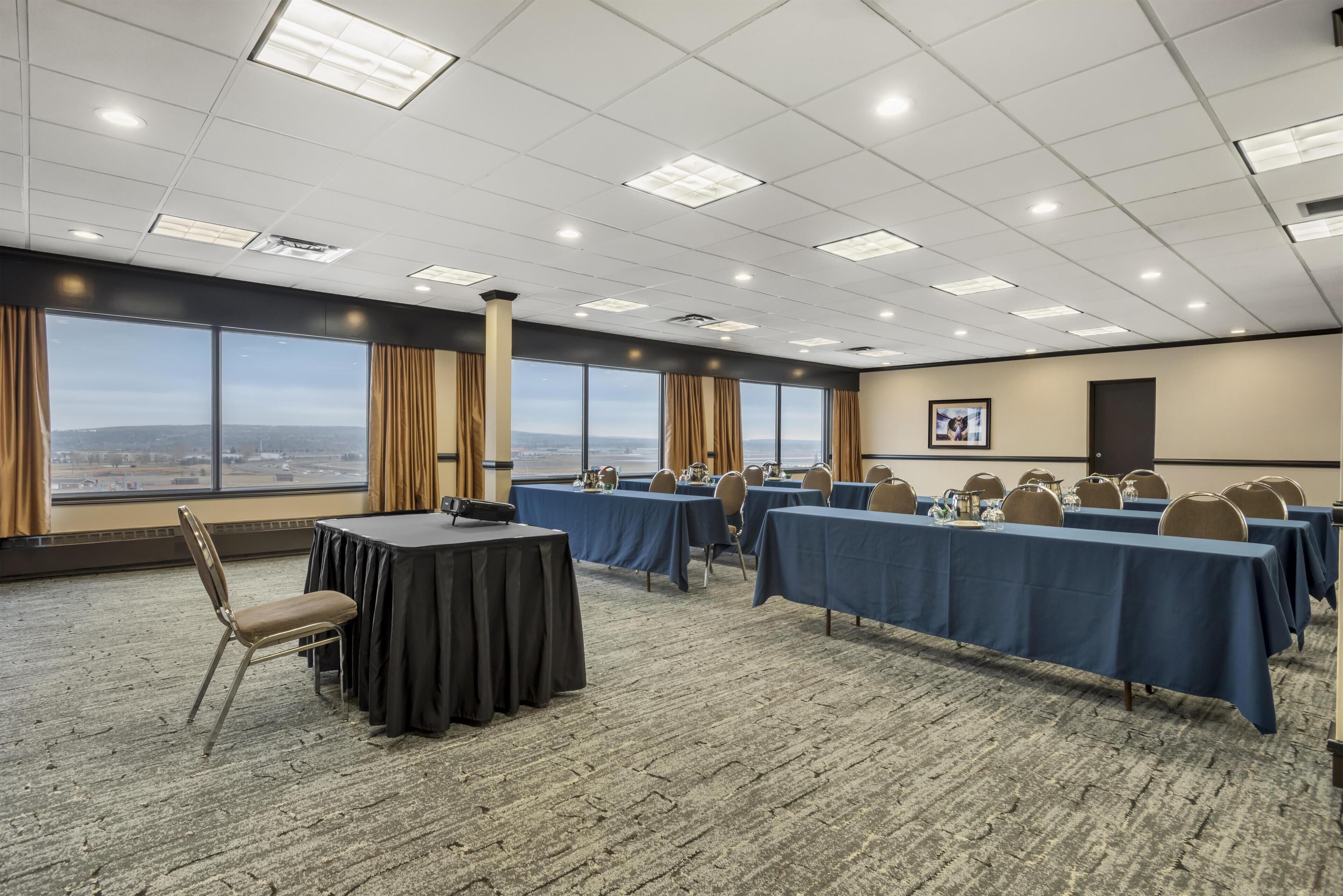 Une salle de conférence équipée de plusieurs tables, de chaises et d’une grande fenêtre offrant une vue panoramique.