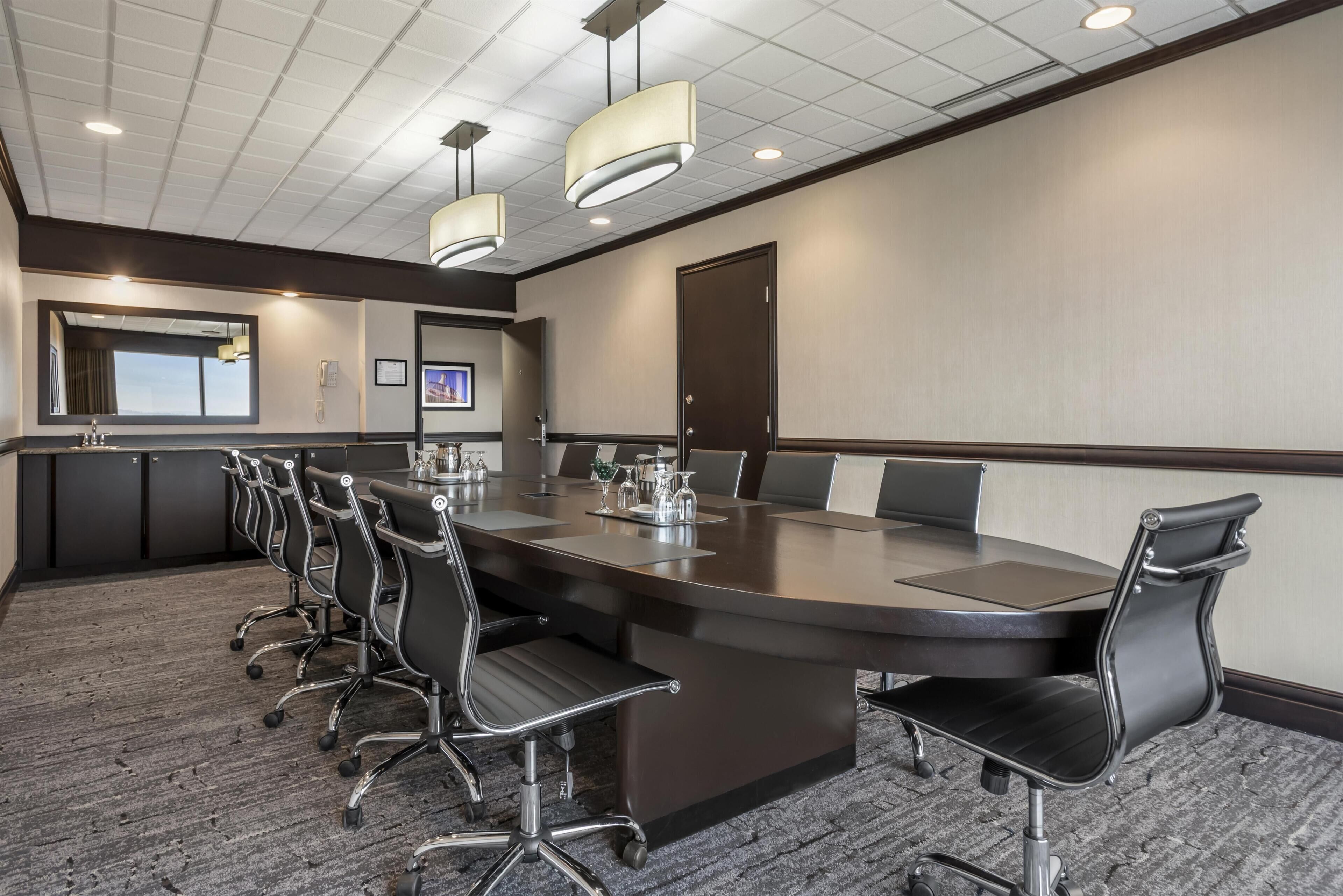A conference room with a long table, multiple chairs, and a large window.