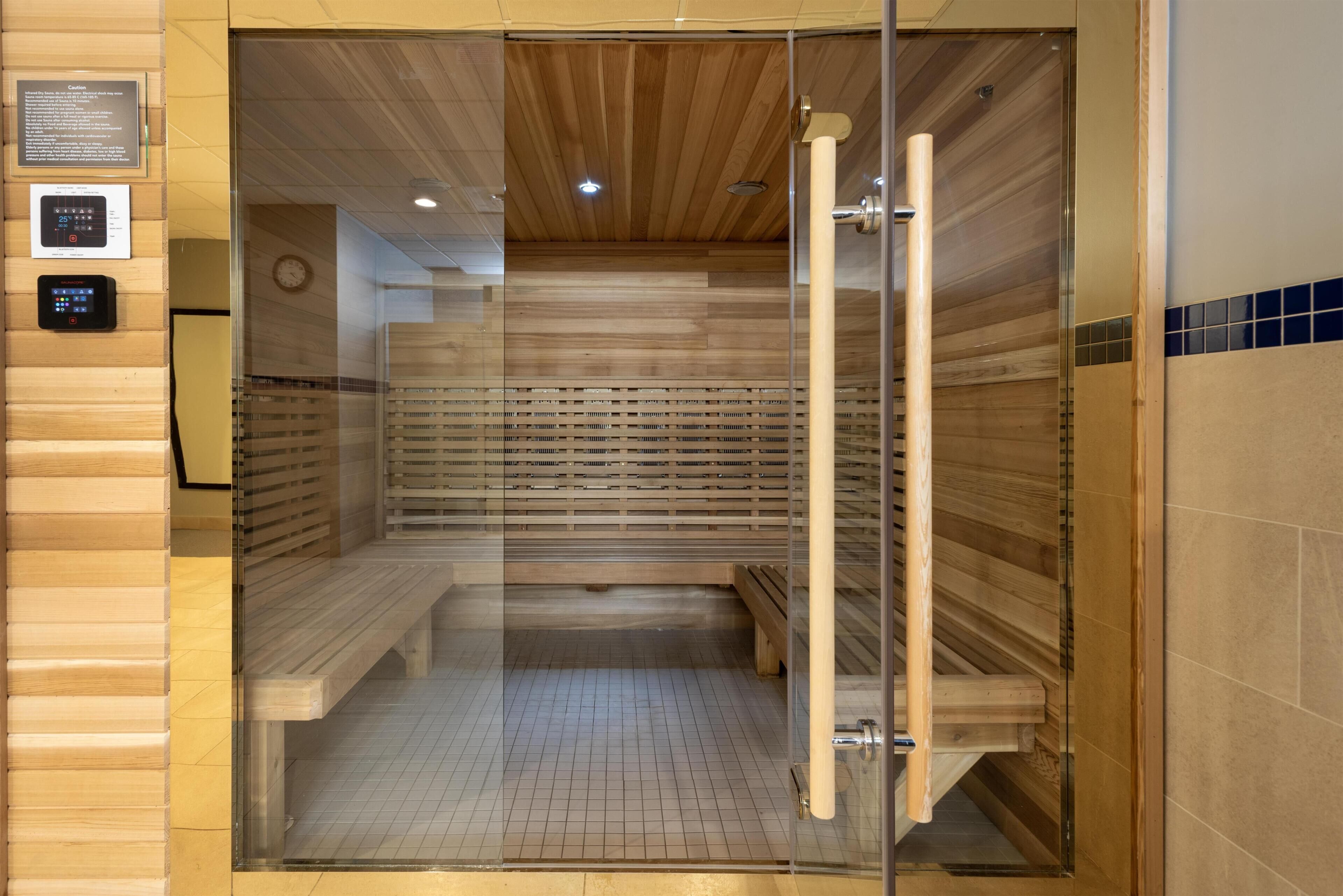 Uma sauna com ripas de madeira, um banco e uma porta de vidro.