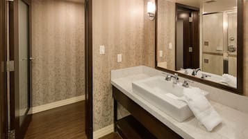 Un bagno d'hotel con un ampio specchio, due lavandini e zona doccia.