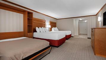 A hotel room with two beds, a wardrobe, a desk, and a lamp.