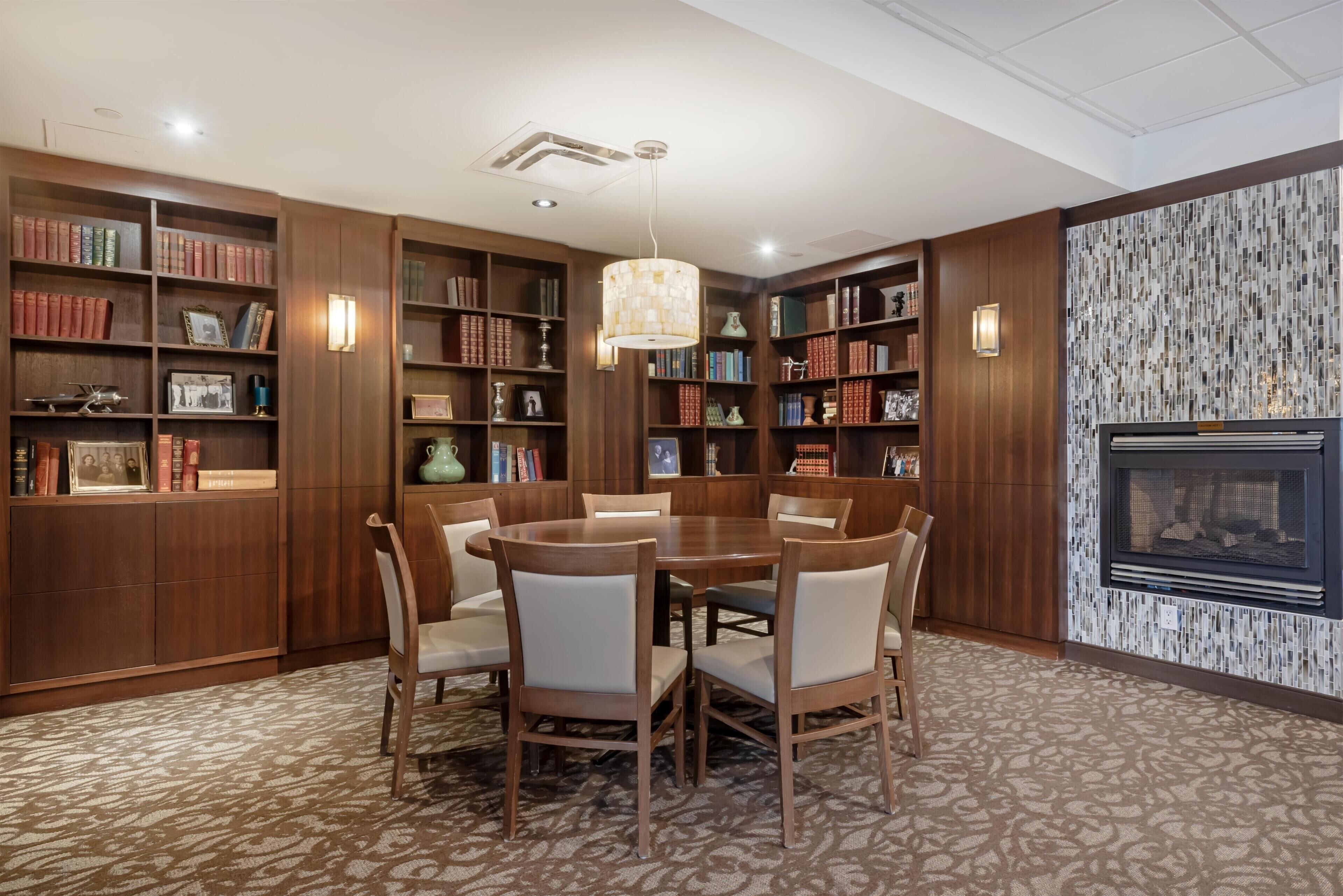 Zona pranzo con un tavolo rotondo e sedie, circondata da librerie piene di libri e oggetti decorativi.