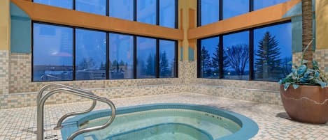 Ein großes Hallenbad mit freiem Blick durch große Fenster, einem gefliesten Boden und einer Metallleiter.