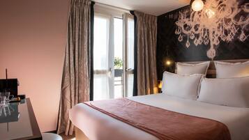Habitación de hotel con una cama grande, un escritorio con silla y un candelabro.