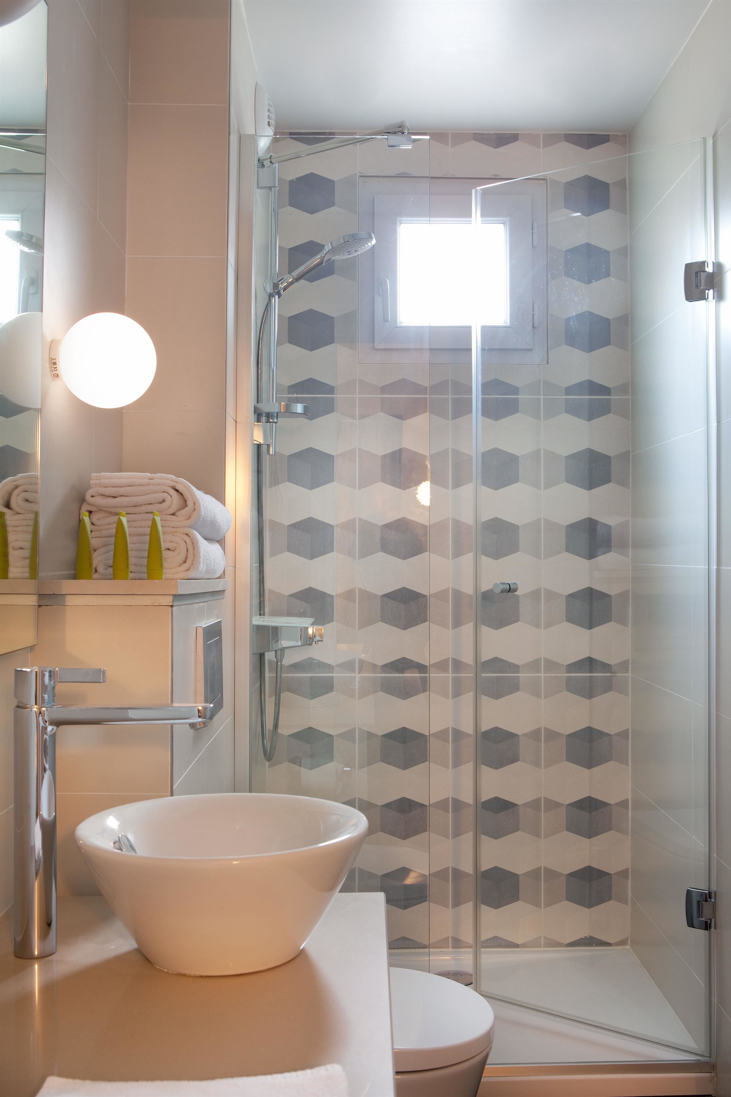 Un baño moderno con cabina de ducha de vidrio, un lavabo blanco y un inodoro.
