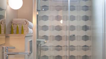Un baño moderno con cabina de ducha de vidrio, un lavabo blanco y un inodoro.