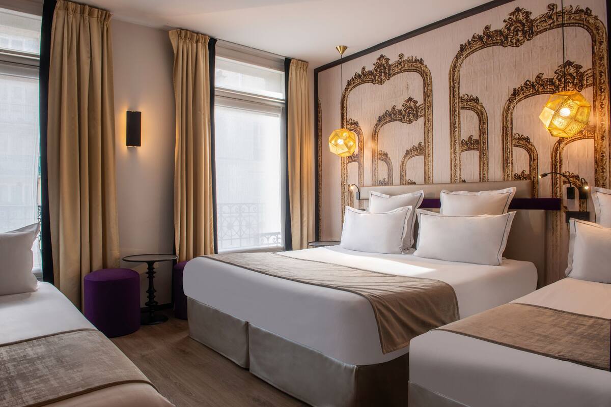 A hotel room with two beds, a large mirror, and a view of the city.
