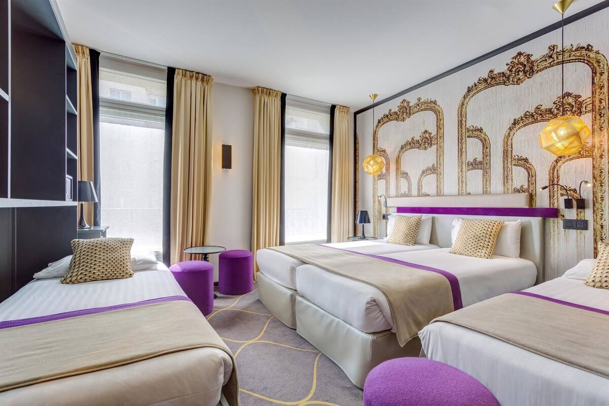 A hotel room with two beds, a large mirror, and a chandelier.